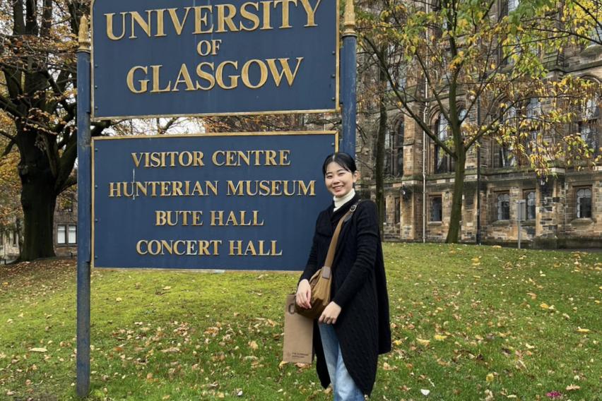 イギリスグラスゴー大学の看板と一緒に写真を撮る生徒