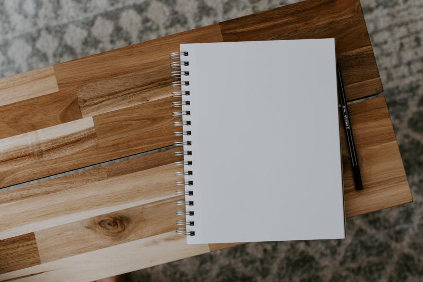 A blank page of a notebook on top of a wooden table.