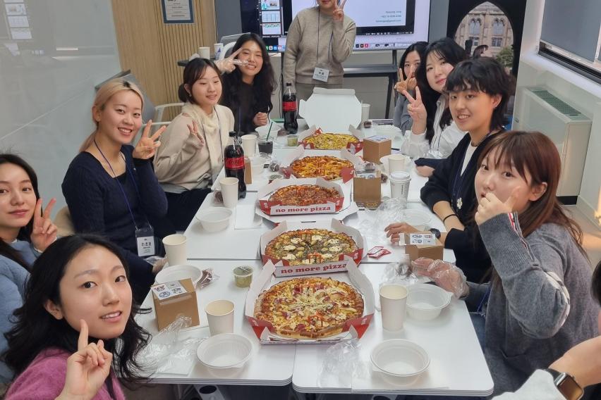 SAF Korea Global Ambassadors gather around a table with pizza during a networking event and career presentations.