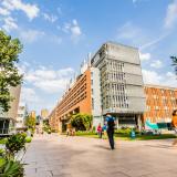 Students make their way to class on UNSW's campus, with tall brick buildings along the main walkway.