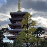 The Sensoji tower with trees and clouds framing it. The tower has a large golden spire at the top.