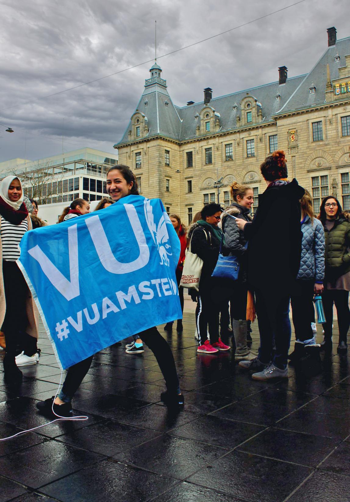 a student walking with a VU flag on a rainy day