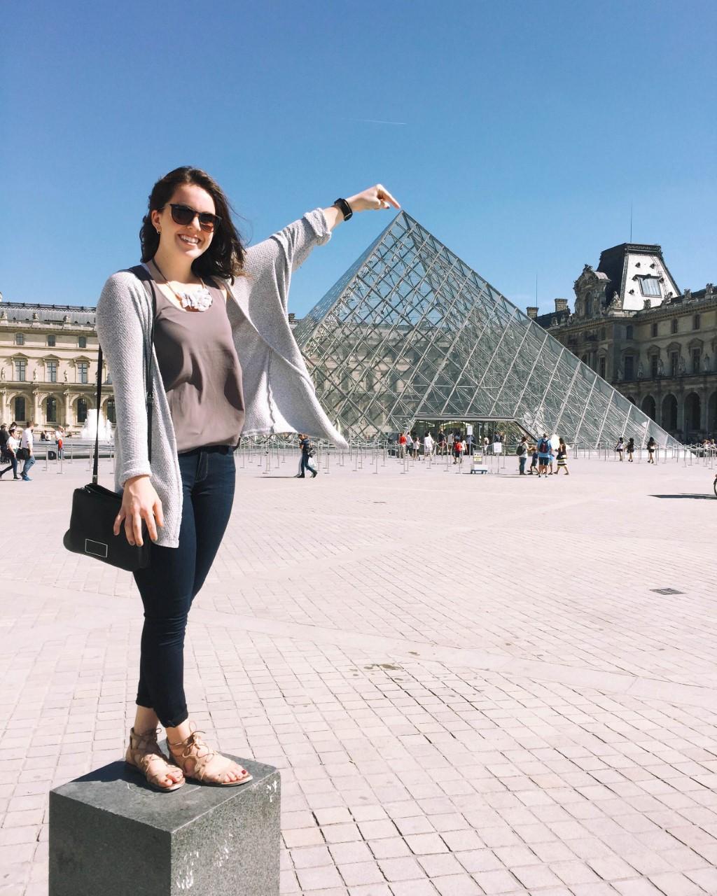 Student at an angle that looks like she is touching the top of the Louvre 