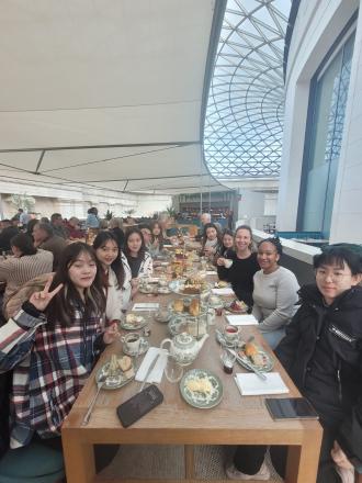 digital marketing students in London gather for afternoon tea around a wooden table in a modern building
