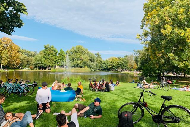 a park in Amsterdam with people and bikes resting on the lawn
