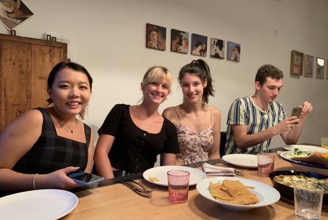 Students with their host mom seated around a dinner table at a homestay in Nice.