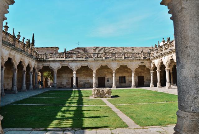 The courtyard at the University of Salamanca. Grass is surrounded by Spanish arch pillars.