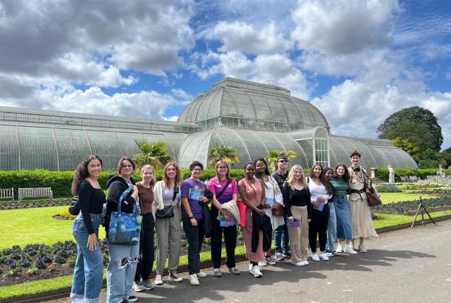 group of london students in front of green grass area and large glassed greenhouse