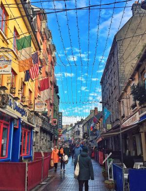 irish side streed at sunset lined with pubs, brick buildings, and a blue sky