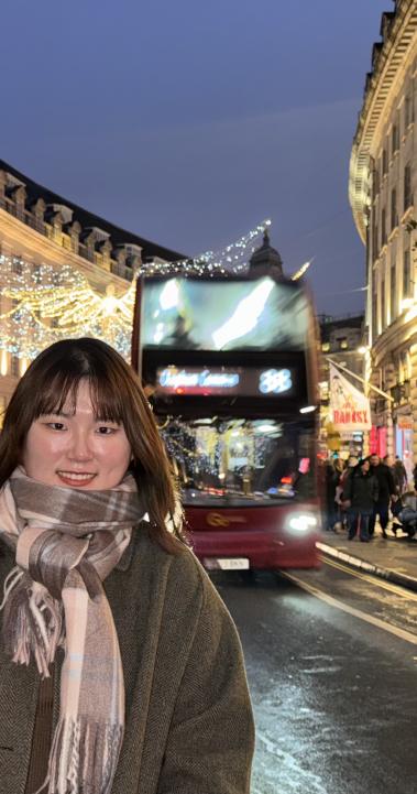 A student poses on the high street of Central London at night