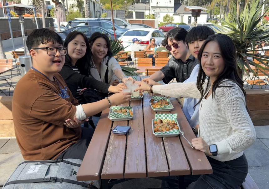 Victoria Lai having lunch and cheersing with students at a picnic table