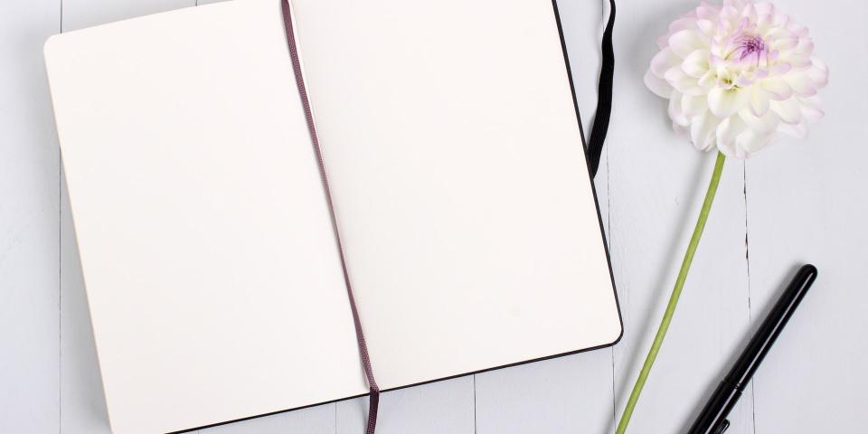 An opened journal with blank pages and pen on a table