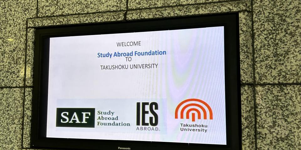 A digital sign for the SAF informational session at Takushoku University
